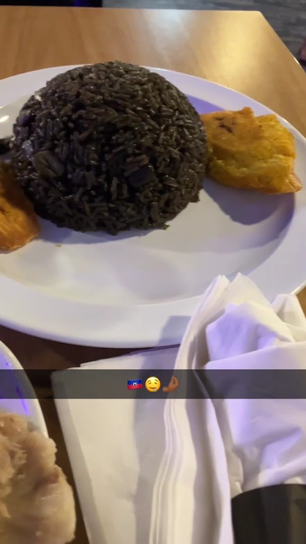 Plated Haitian dishes on a restaurant table.
